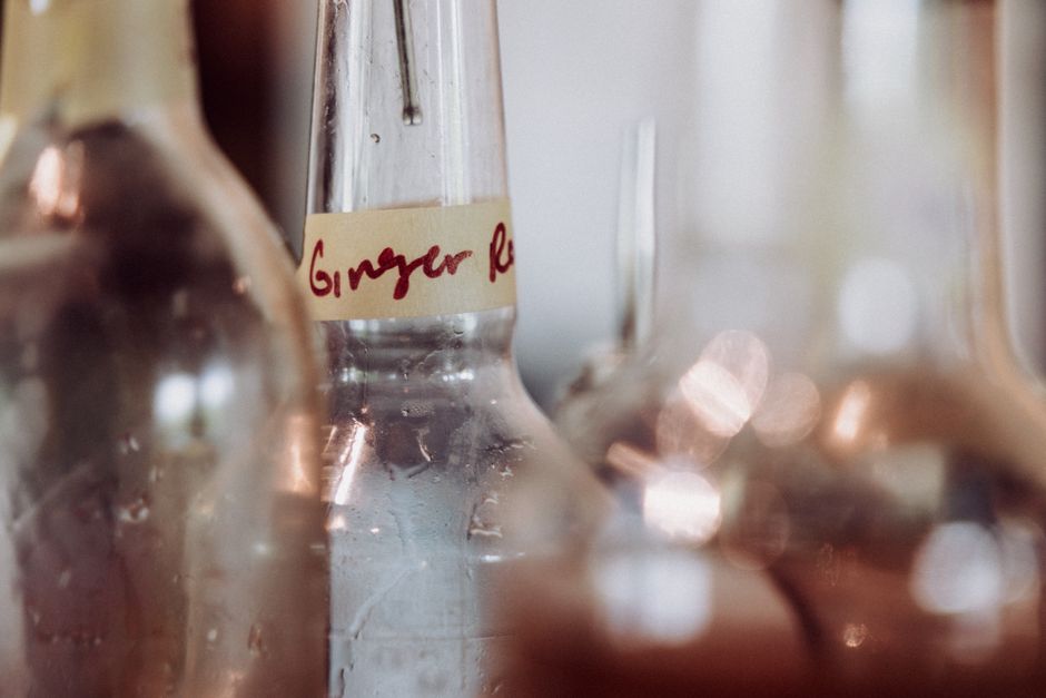 Artistic close-up of bottles focusing on "Ginger" label with blurred background.